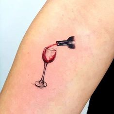 a woman's arm with a wine glass tattoo on it