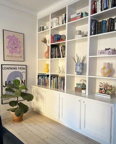 a living room filled with lots of white bookshelves