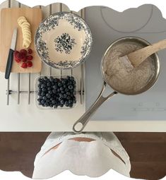 a pan filled with blueberries and raspberries on top of a counter next to other kitchen utensils