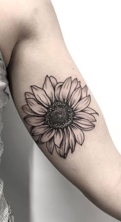 a black and white sunflower tattoo on the arm