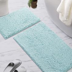 two bathroom rugs sitting next to each other on a white counter top with silver slippers