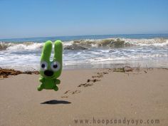 a green stuffed animal is on the beach