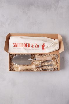 an open box with some utensils and a knife in it on a table