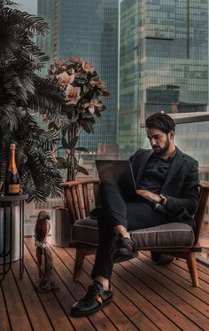 a man sitting in a chair on top of a wooden floor next to a plant