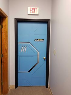 an exit sign is on the wall above a blue door that leads to another room