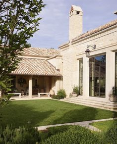 a large house with a clock tower in the back yard and green grass on the front lawn