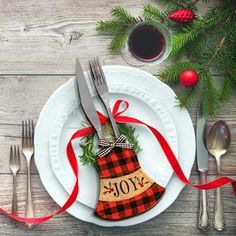 a white plate topped with a christmas stocking on top of a table next to silverware