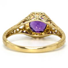 An approximate 0.93ct deep-purple amethyst is prong set in this lovely Edwardian style filigree mounting. The stone, nestled in an octagonal setting, is held in place with eight low profile prongs and surrounded by a circle of gold milgraining. The ring is beautifully filigreed and the band is embellished with a wheat style engraving. Added bonus: amethyst is the birthstone of February! Metal: 14K Yellow Gold Main Stone: 1 Round Cut Amethyst (approx. 0.93ct, 6.53 mm) Ring Size: 7.0 (can be sized Oval Purple Filigree Amethyst Ring, Oval Purple Amethyst Ring With Filigree, Purple Oval Amethyst Ring With Filigree, Purple Amethyst Ring With Intricate Design, Classic Amethyst Ring With Bezel Setting, Classic Purple Amethyst Ring With Bezel Setting, Formal Purple Amethyst Ring With Filigree, Heirloom Style Purple Amethyst Ring With Bezel Setting, Heirloom Purple Amethyst Ring With Bezel Setting