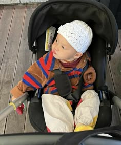 a baby sitting in a stroller wearing a hat