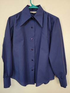 "Yep, smart! Be smart! It's a Vintage 1970s Miss Holly dark blue polyester crepe long sleeve pointy collar blouse! Measured women's bust 40\" Dark blue crepe-like polyester with long pointy collar. Fun purple buttons. Shirt looks and feels unworn to me! It's neat. And smart! Please see our other listings for more vintage 70s garments with new items added nearly daily. If you like the old quality every day wear clothing - I gotcha covered! PLEASE check the measurements as vintage clothing sizes may not comparable to contemporary sizes. Measurements: Label size: vintage 34 Shoulder-to-shoulder: 16\" Chest across: 20\" Sleeve from shoulder: 22\" Length in back from base of collar: 24\" Pete's Obsolete is smoke-free. We present garments as honestly as possible and point out any known flaws. We Fitted Blouse With Buttons And Lapel Collar, Fitted Blouse With Lapel Collar And Buttons, Fitted Solid Color Blouse With Spread Collar, Fitted Collared Blouse With Button Cuffs, Fitted Spread Collar Blouse For Fall, Fitted Blouse With Spread Collar For Fall, Vintage Long Sleeve Office Tops, Vintage Long Sleeve Tops For Office, Blue Fitted Top With Lapel Collar