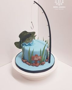 a blue cake with a fish on it and some green plants in the bottom half