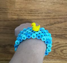 a yellow rubber ducky sitting on top of a blue beaded bracelet with circles