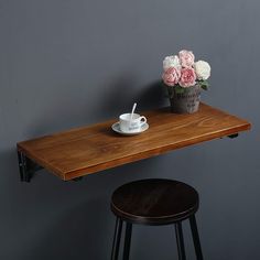 a wooden table topped with a white cup and saucer next to a flower pot