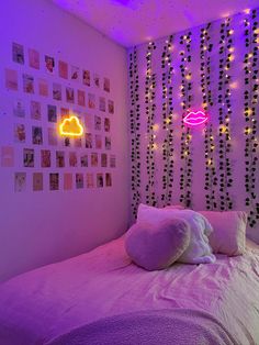 a bedroom with purple lights and pictures on the wall above the bed, along with a pink comforter