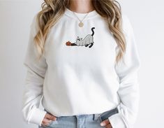 Check out this cute cat ghost embroidered sweatshirt or hoodie for halloween! Features a ghost cat next to a jack-o-lantern. Click to get yours today! Creep it REAL for spooky season with this adorable cat ghost sweatshirt. Perfect for cat lovers and those who love halloween clothing!  Choose from a sweatshirt or hoodie! See listing photos for size guides! 2XL - 5XL available upon request. Send me a message on Etsy! :) Available in 8 colors! Check out the homepage of my shop for more products that'll surely make you laugh or smile!: https://www.etsy.com/shop/tintedhappytees RETURNS AND REFUNDS I do not accept returns and exchanges as this is a custom product. I don't accept cancellations (unless I haven't started on your order yet), but please contact me if you have any problems with your Fall Long Sleeve Hoodie With Cat Print, White Long Sleeve Sweatshirt With Cat Print, Casual Halloween Sweatshirt With Cat Design, Fall Crew Neck Sweatshirt With Cat Design, Casual Halloween Sweatshirt With Cat Print, White Cat Design Sweatshirt For Fall, Embroidered Halloween, Cat Ghost, Creep It Real