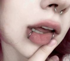 a close up of a person with pink hair and piercings on her nose,