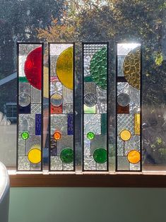 three stained glass panels sitting on top of a window sill