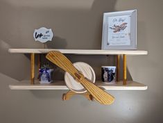 two wooden shelves with plates and utensils on them, one holding a paddle