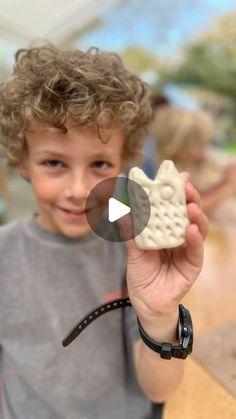 a young boy holding up a cookie in his hand