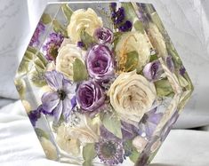 a glass vase filled with flowers on top of a bed