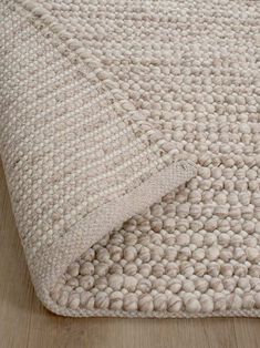 a white rug on top of a wooden floor with a wood floor in the background