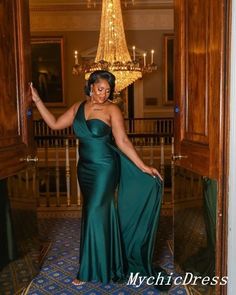 a woman in a green dress is standing at the entrance to a room with chandelier