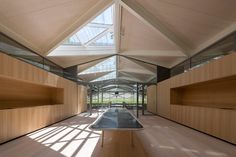 the inside of a building with wooden walls and glass windows on one side, and wood flooring on the other