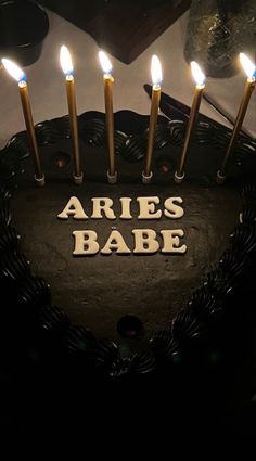 a heart shaped cake with lit candles on it that says aries babe in the center