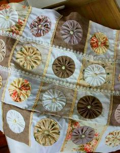 an old quilt with many different designs on it's sides and some buttons in the middle