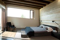 a bedroom with a bed, chair and window in the room that looks out onto the outdoors