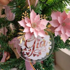 a glass ornament hanging from a christmas tree decorated with pink and gold paper flowers