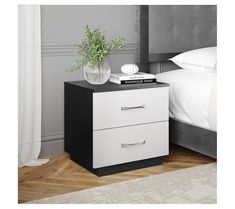 a white nightstand with two drawers and a plant on top of it next to a bed