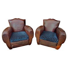 two brown leather chairs with blue cushions on each one and the other facing opposite directions