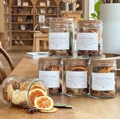 several jars filled with dried fruit and nuts on top of a wooden table next to a potted plant