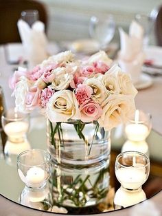 a vase filled with lots of white and pink flowers on top of a glass table