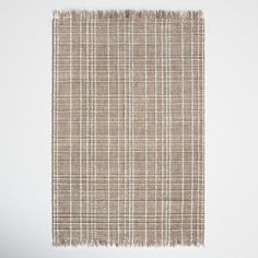 a brown and white plaid rug with fringes on the bottom, in front of a wall