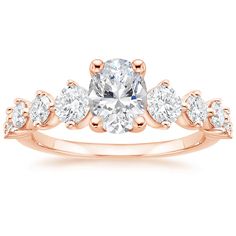 a rose gold engagement ring with three stones on the band and an oval center stone