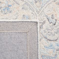 an area rug with blue and white designs on the side, in front of a gray background