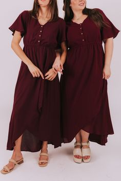 two women standing next to each other wearing dresses with short sleeves and buttons on the front