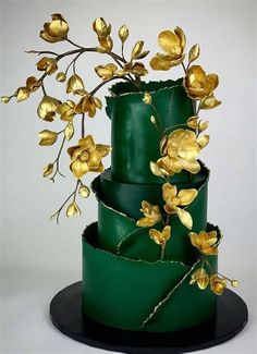 a three tiered green cake with gold flowers on top