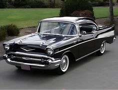 an old black and white car parked on the street