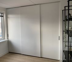 an empty room with white sliding doors and wood flooring