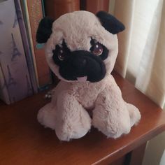 a stuffed animal sitting on top of a wooden table next to a bookshelf