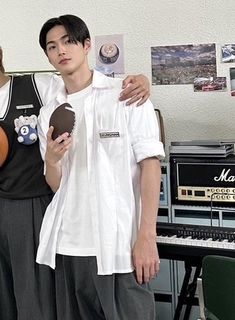 two young men standing next to each other in front of a desk with musical equipment