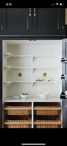 an open pantry with baskets and bowls in the bottom shelf, next to shelves on both sides