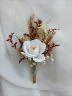 a boutonniere with white flowers and dry grass on it's side