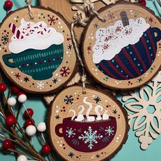 three wooden ornaments with designs on them and snowflakes hanging from the tree branch