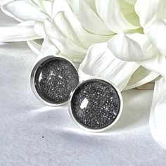 This eye and light catching earring set features silver plated stud earrings filled with sparkling iron filings and topped with a glass cabochon. Celebrate 6 years of marriage in style! Earrings: approx 12mm diameter. Boxed in a luxury box with magnetic closure.  All of our jewellery boxes are eco friendly and FSC certified. See our complete range of Iron (6th) Anniversary Gifts here: https://www.etsy.com/uk/shop/HandmadeAnniversary?ref=seller-platform-mcnav&section_id=39413722 NOTE: All of our items are handmade and therefore slight variations may occur.  Colours may appear different depending on your screen settings. Shipping We offer free shipping to the UK.  All items are posted by Royal Mail 2nd Class and, if ordered by 3pm Monday to Friday, will be with the Post Office by 5pm on the Silver Glitter Round Earrings, Gift Silver Nickel Free Clip-on Earrings, Adjustable Silver Glitter Jewelry, Minimalist Silver Sparkling Earrings, Minimalist Silver Earrings With Sparkling Details, Glitter Round Jewelry As Gift, Round Glitter Jewelry As Gift, Round Glitter Jewelry For Gifts, Sparkling Silver Earrings For Gift