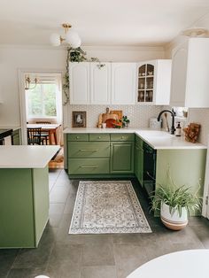 a kitchen with green cabinets, white counters and an area rug on the floor in front of the sink