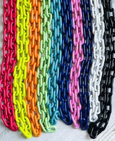 a bunch of different colored chains sitting on top of a white wooden table next to each other